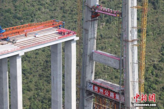 11月22日，峰林特大橋4號主塔中橫梁正在吊裝。當日，隨著1470噸裝配化預制中橫梁提升到位，貴州省黔西南布依族苗族自治州興義環(huán)城高速公路峰林特大橋4號主塔中橫梁成功吊裝，由此刷新了山區(qū)峽谷橋梁預制吊裝混凝土構件重量世界記錄。峰林特大橋是屬全線控制性工程。大橋跨越馬嶺河峽谷，全長1163米，主跨采用550米懸索橋，橋面離谷底364.2米，是中國山區(qū)第一座大跨徑鋼混疊合梁懸索橋。中新社記者 瞿宏倫 攝