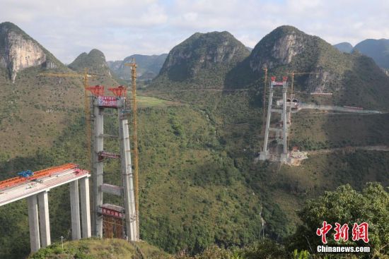 11月22日，正在建設中的峰林特大橋。當日，隨著1470噸裝配化預制中橫梁提升到位，貴州省黔西南布依族苗族自治州興義環(huán)城高速公路峰林特大橋4號主塔中橫梁成功吊裝，由此刷新了山區(qū)峽谷橋梁預制吊裝混凝土構件重量世界記錄。峰林特大橋是屬全線控制性工程。大橋跨越馬嶺河峽谷，全長1163米，主跨采用550米懸索橋，橋面離谷底364.2米，是中國山區(qū)第一座大跨徑鋼混疊合梁懸索橋。中新社記者 瞿宏倫 攝